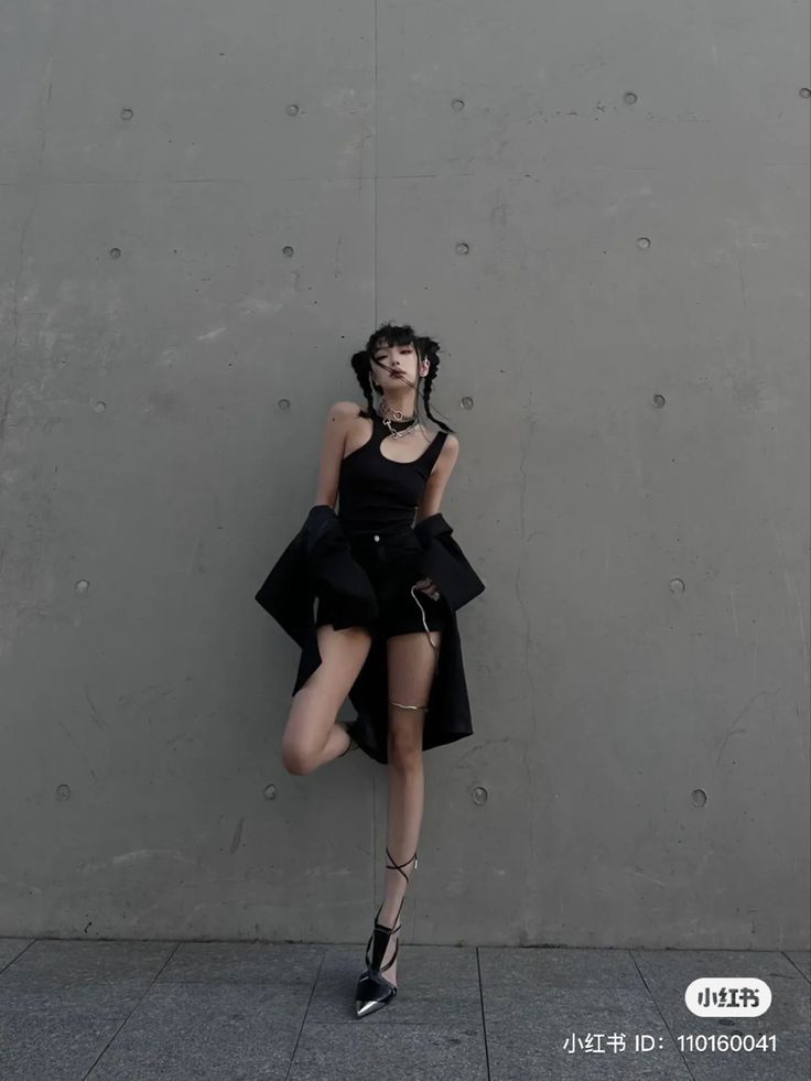 a woman is posing in front of a wall