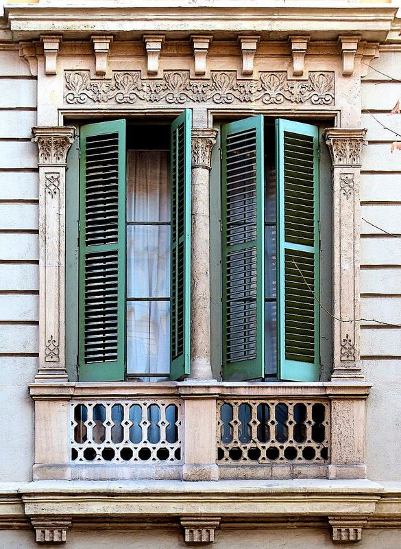 an old building with green shutters on the windows and balconies in front