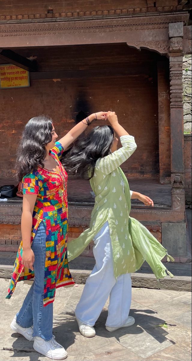 two women dancing in front of an old building