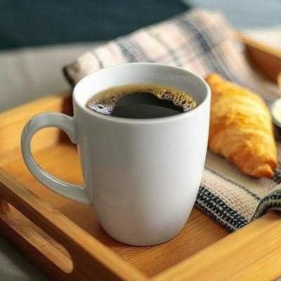 a cup of coffee and some croissants are on a tray with a blanket