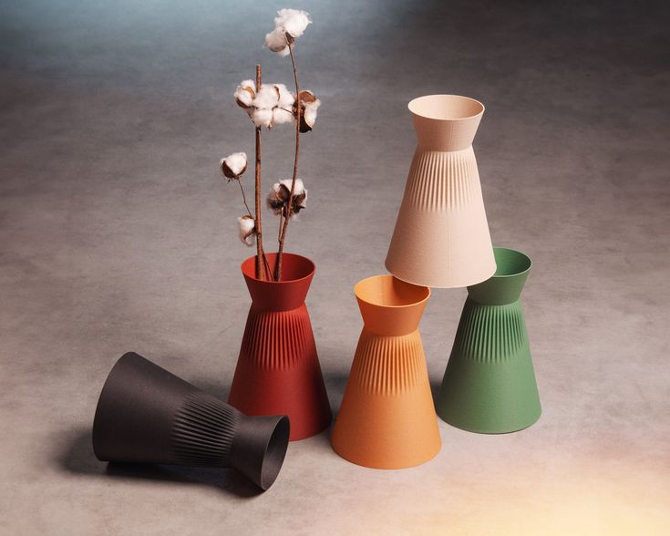 three different colored vases sitting next to each other on a gray surface with flowers in them