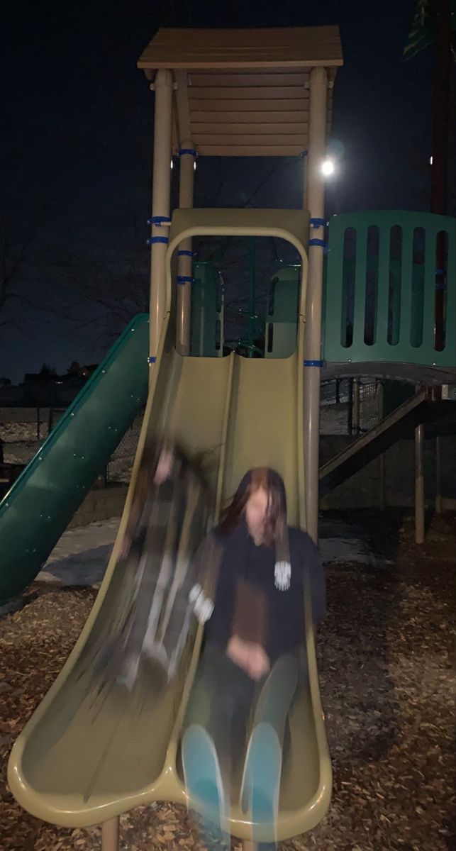 two children playing on a slide at night