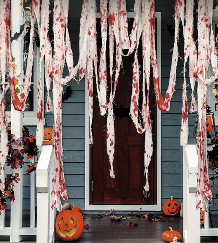 a porch decorated for halloween with pumpkins and icing hanging from the front door