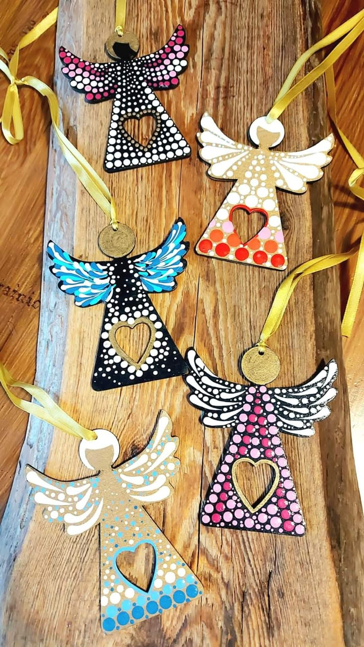 an assortment of angel ornaments on a wooden board with yellow ribbons and tags attached to them