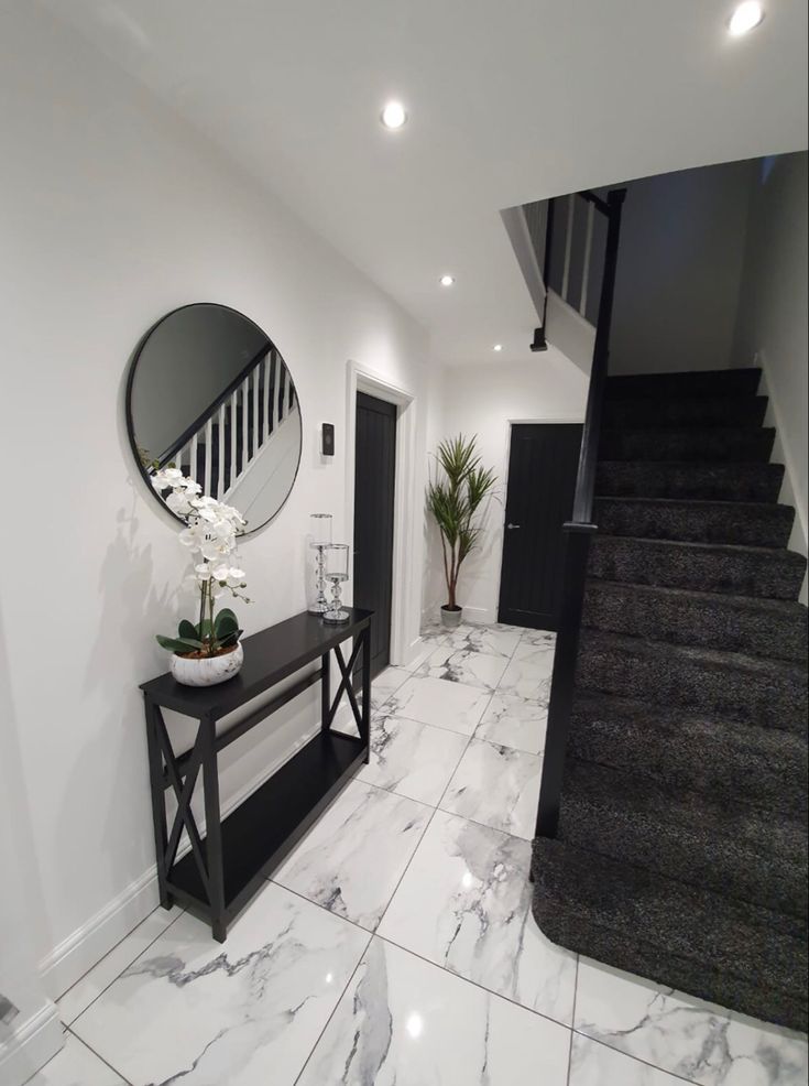 a foyer with marble flooring and white walls, along with a black console table