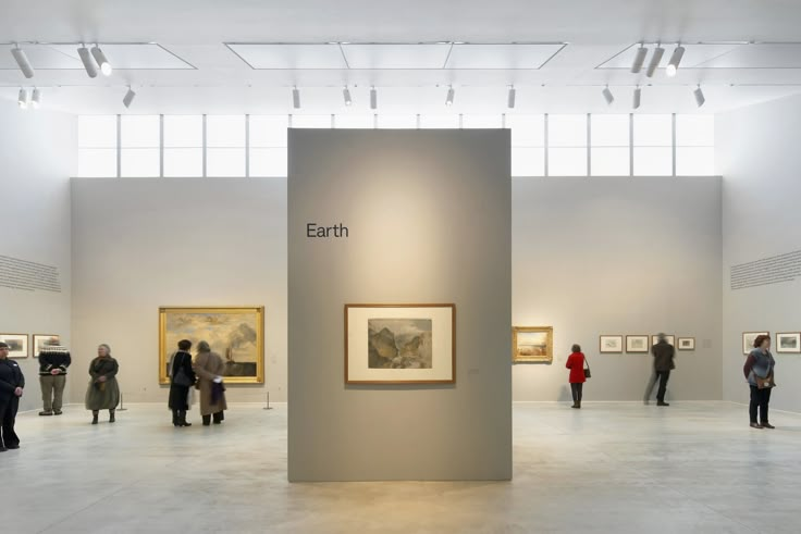 an art gallery with people looking at paintings on the walls and in the middle there is a white floor