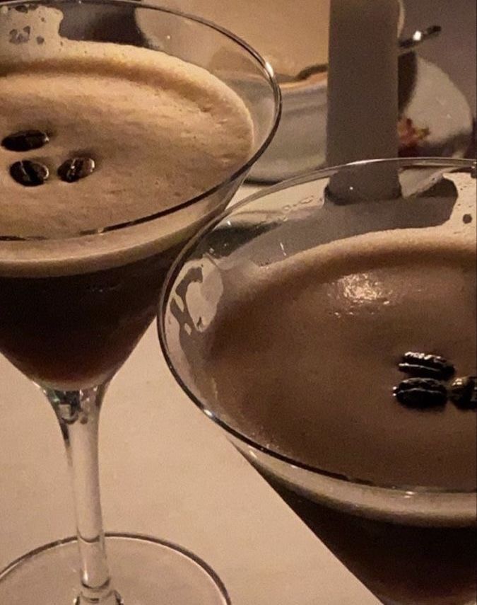 two glasses filled with liquid sitting on top of a white countertop next to each other