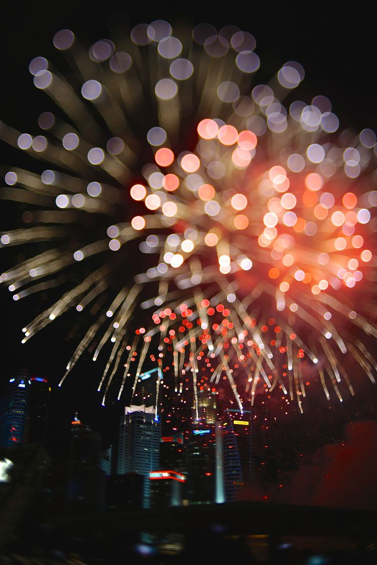 fireworks are lit up in the night sky above a cityscape with buildings and skyscrapers