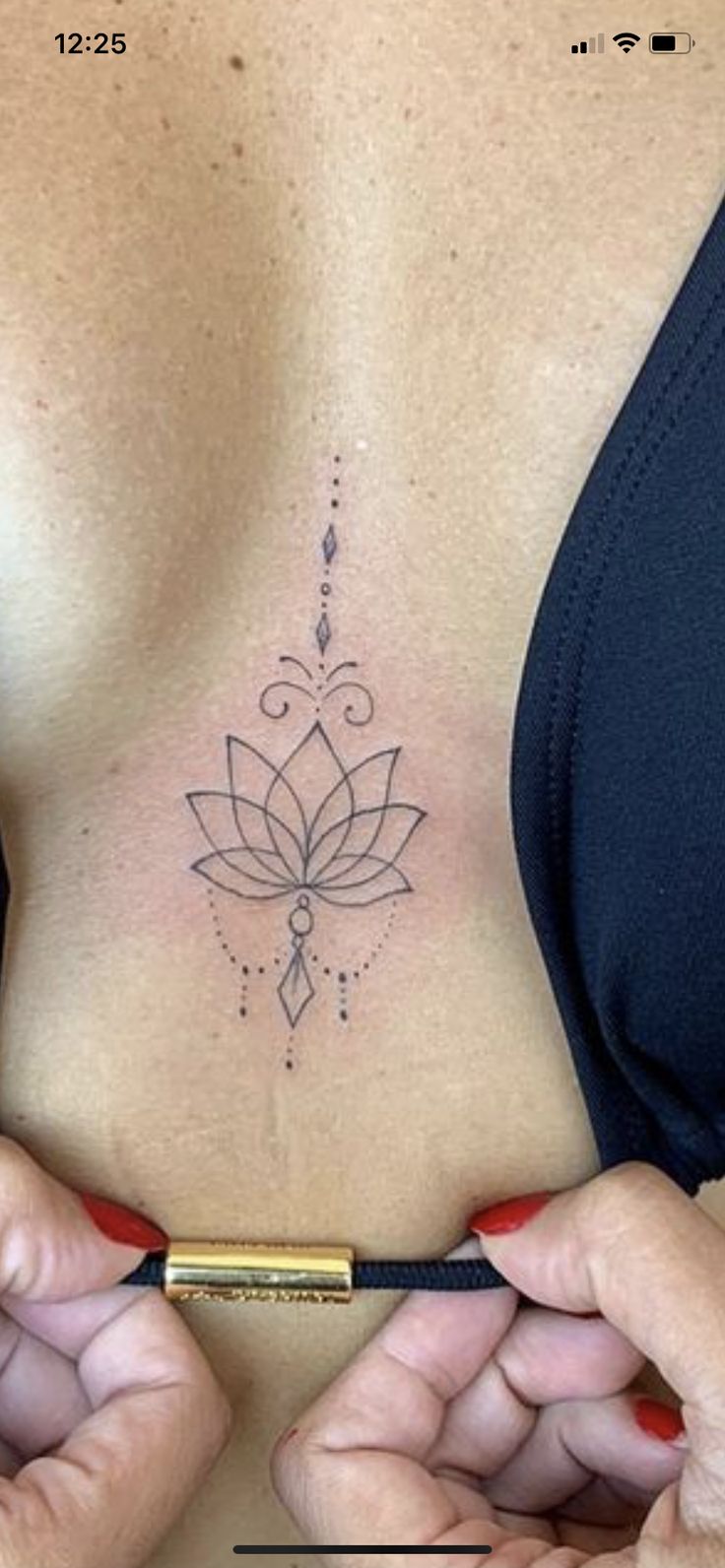 a woman with a lotus tattoo on her chest holding a pencil in front of her stomach