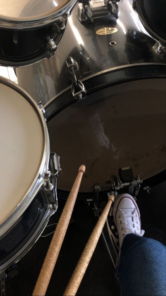 a person with their feet on the drum sticks in front of a set of drums