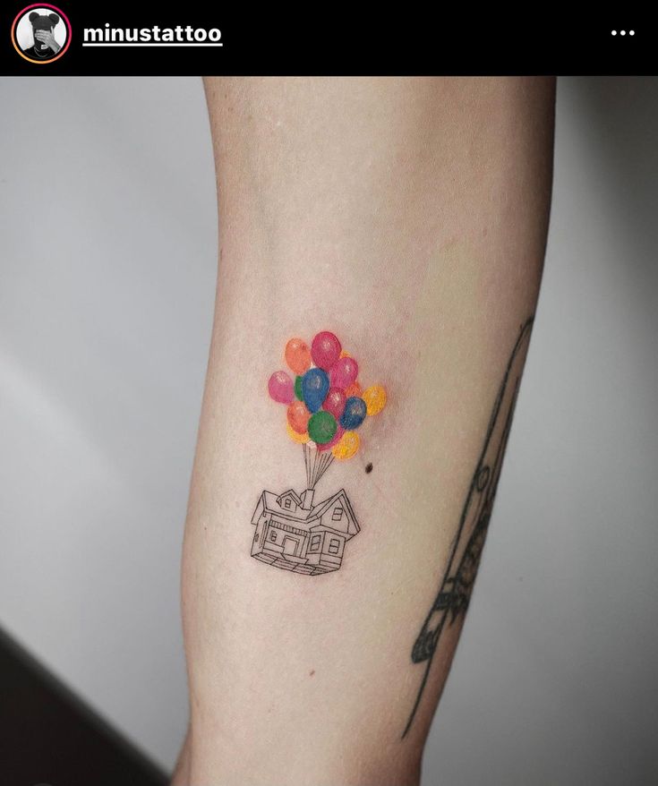 a small tattoo with a house and balloons on it