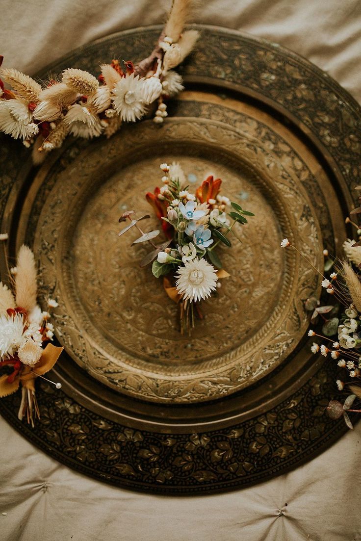 an overhead view of a plate with flowers and feathers around it on a table cloth