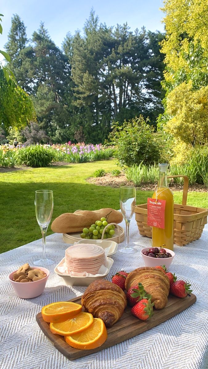 a picnic table with fruit, bread and wine on it in the park or garden