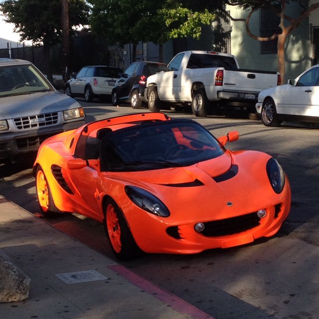 an orange sports car is parked on the street