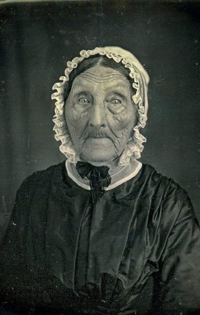 an old black and white photo of a woman wearing a bonnet looking at the camera