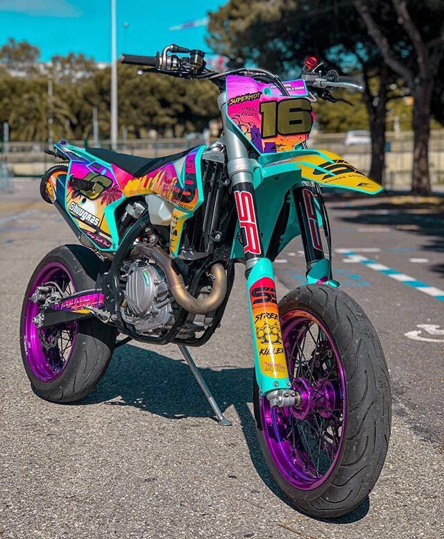 a colorful dirt bike is parked on the street