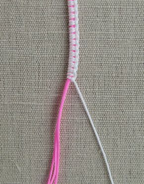 a pink and white crochet toothbrush holder on a beige surface with a light pink handle