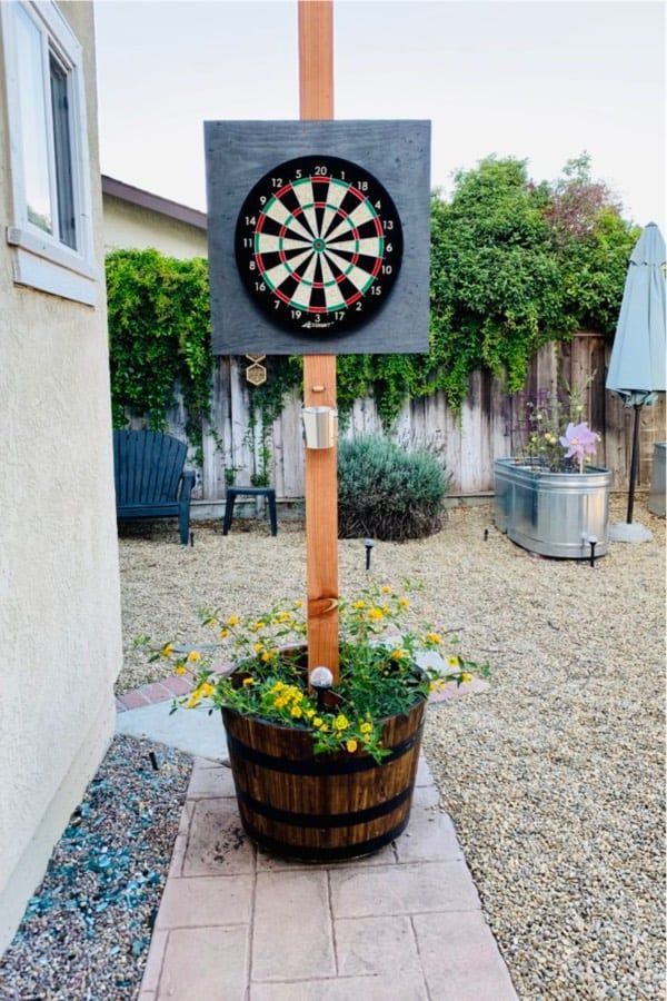 a dart board mounted to the side of a wooden pole next to a potted plant