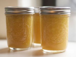 three jars filled with yellow liquid sitting on top of a white countertop next to each other