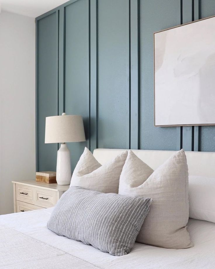 a bedroom with blue walls and white bedding