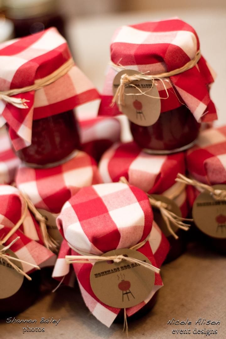 small jars filled with jam sitting on top of a wooden table covered in red and white checkered paper