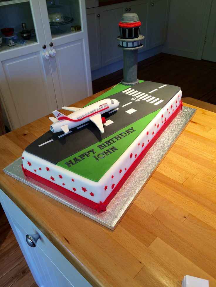 a birthday cake with an airplane on it sitting on top of a wooden countertop