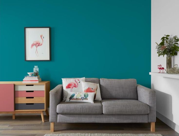 a living room painted in teal and pink, with a grey couch next to it