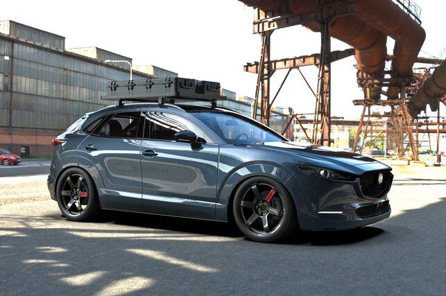 a grey car parked in front of a large industrial building with pipes on the roof