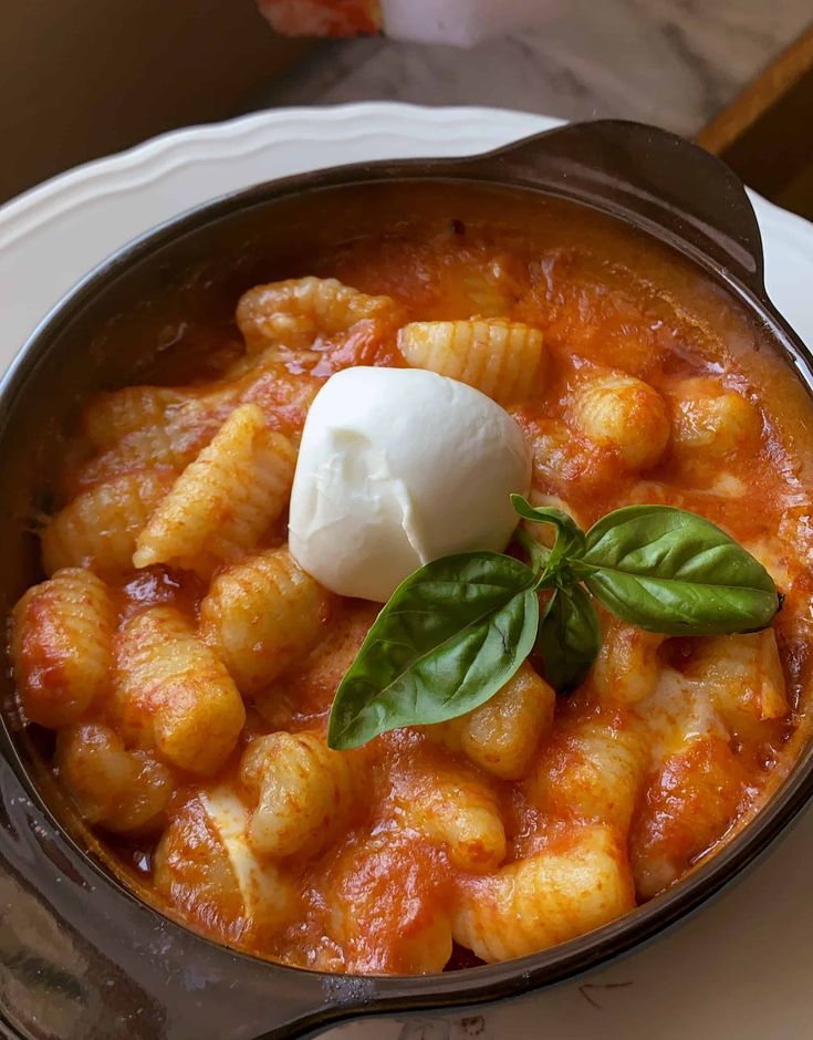 a bowl filled with pasta and cheese on top of a white plate