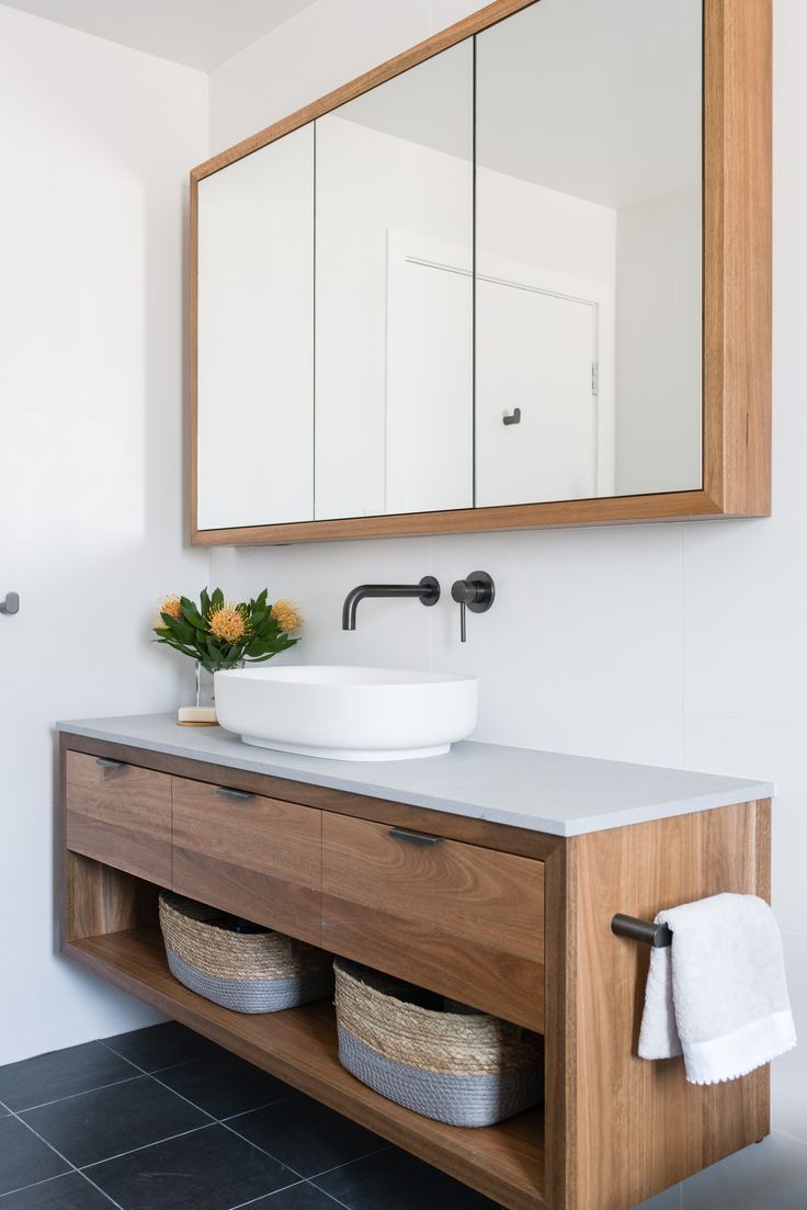 a bathroom with a sink, mirror and towel rack in it's center area