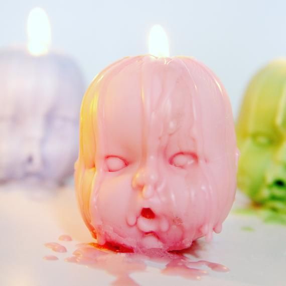 three candles that have been turned on to look like babies'heads with blood running down them