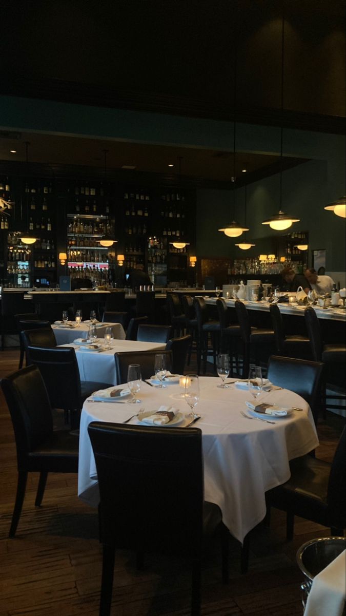 a restaurant with tables and chairs covered in white tablecloths, plates and silverware