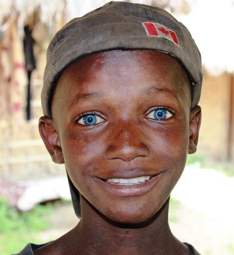 a young boy with blue eyes wearing a hat