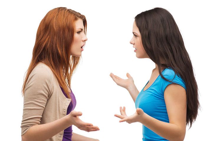 two young women talking to each other while standing in front of a white background photo