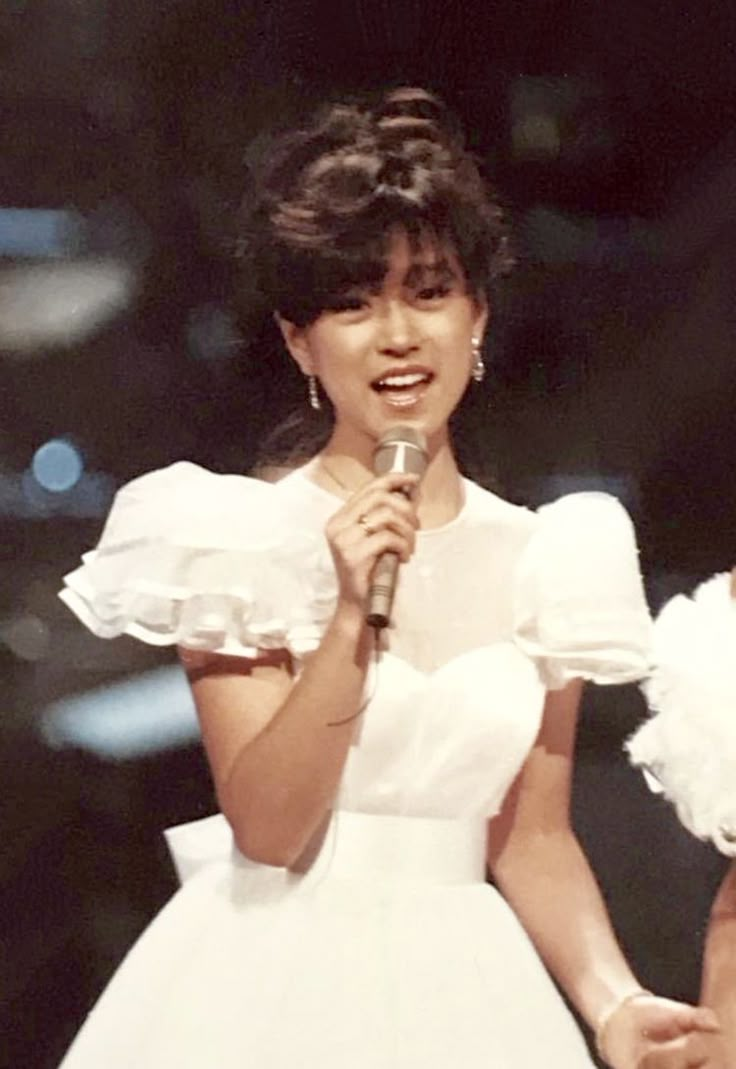 a woman in a white dress holding a microphone