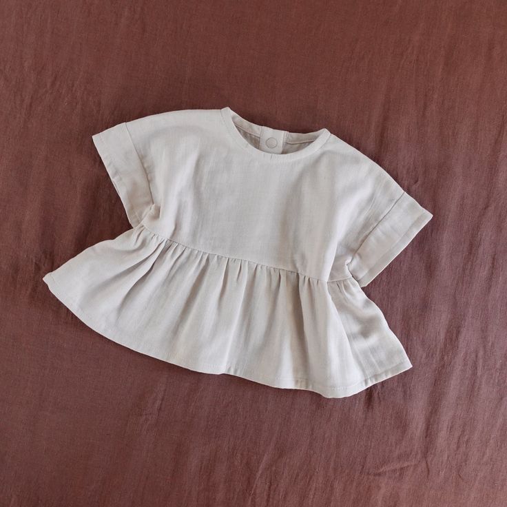 a white shirt with ruffles on it laying on a brown bedclothe