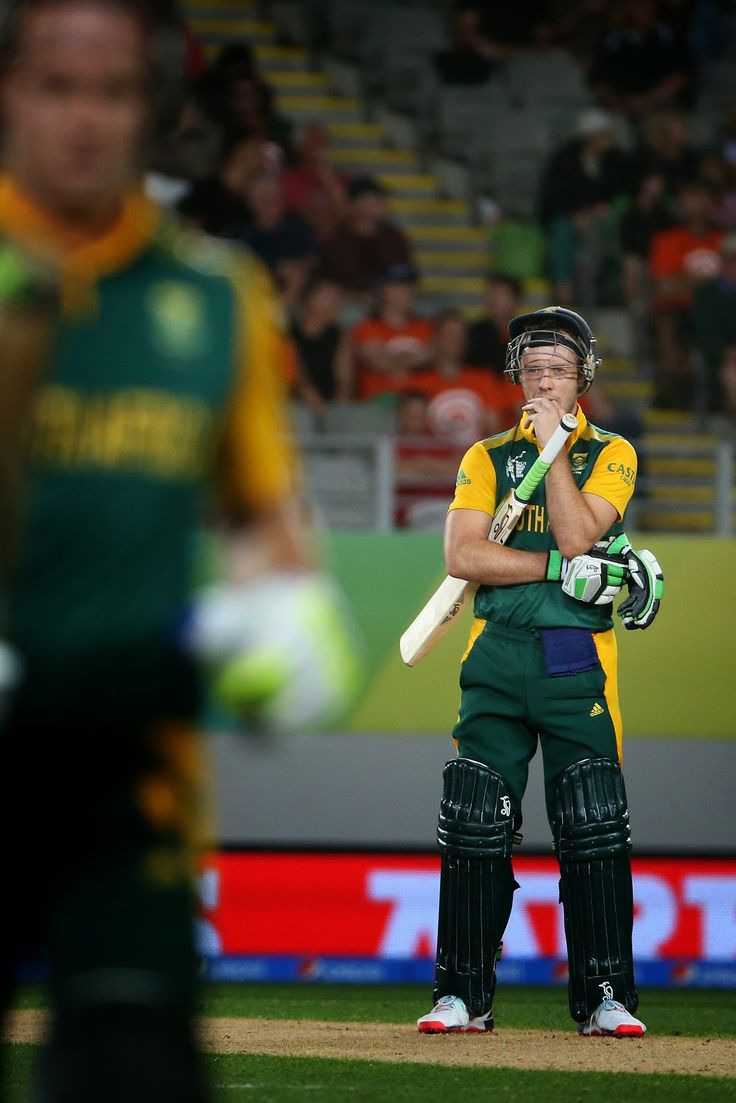 a man in green and yellow uniform holding a baseball bat on a field with people watching