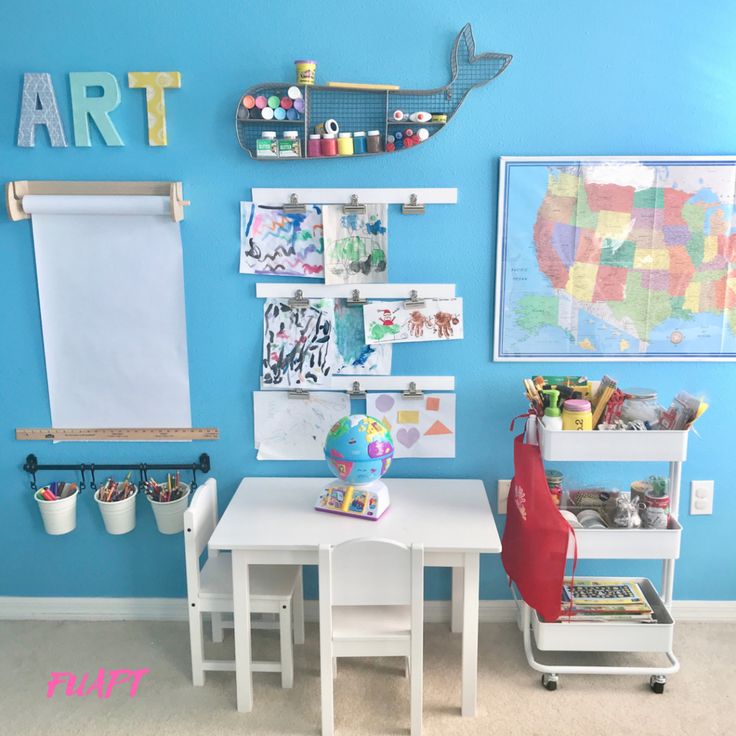 a child's playroom with blue walls and white furniture, including a small table