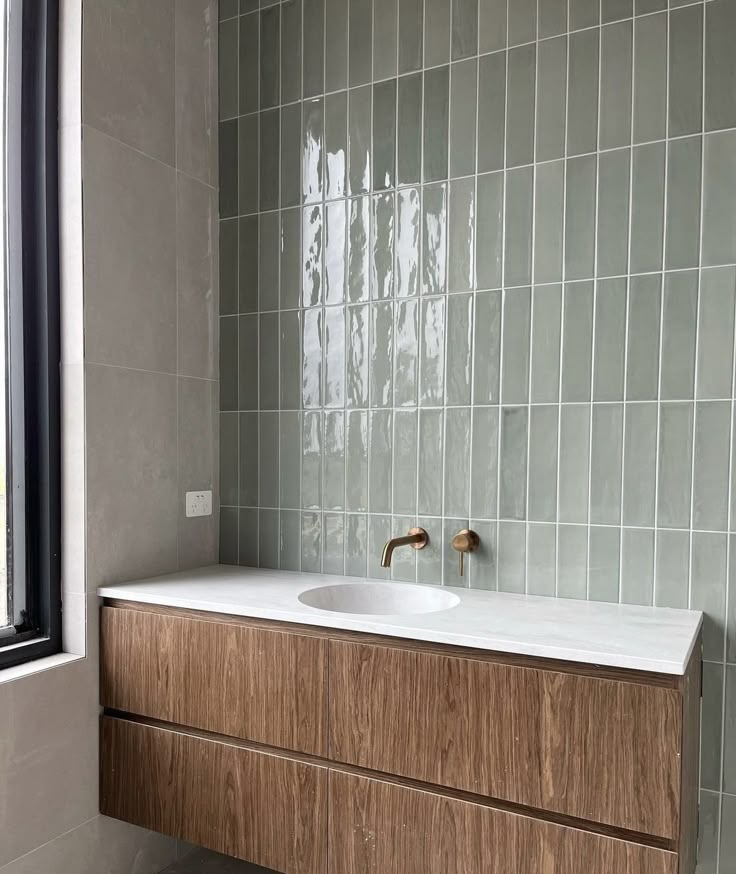 a white sink sitting under a window next to a wooden cabinet with drawers underneath it