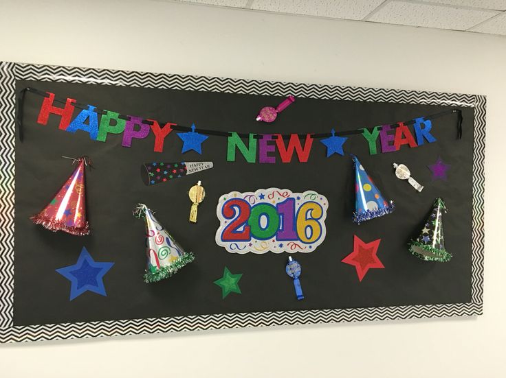 a happy new year sign with party hats and streamers hanging on the wall in an office