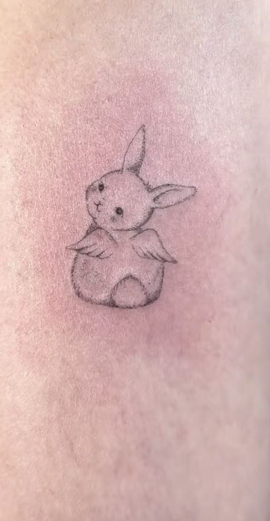 a small tattoo on the back of a woman's stomach, depicting a little bunny