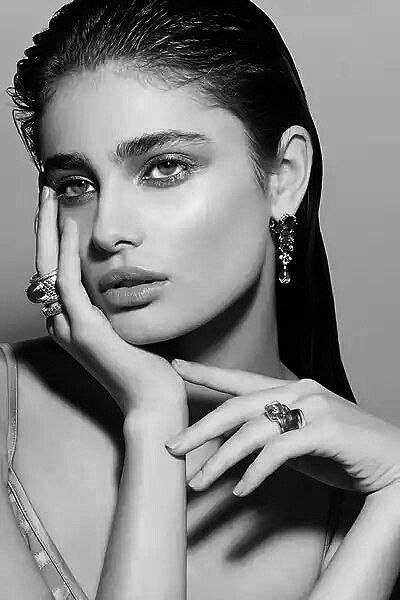 a woman with her hands on her face and wearing jewelry, posing for the camera