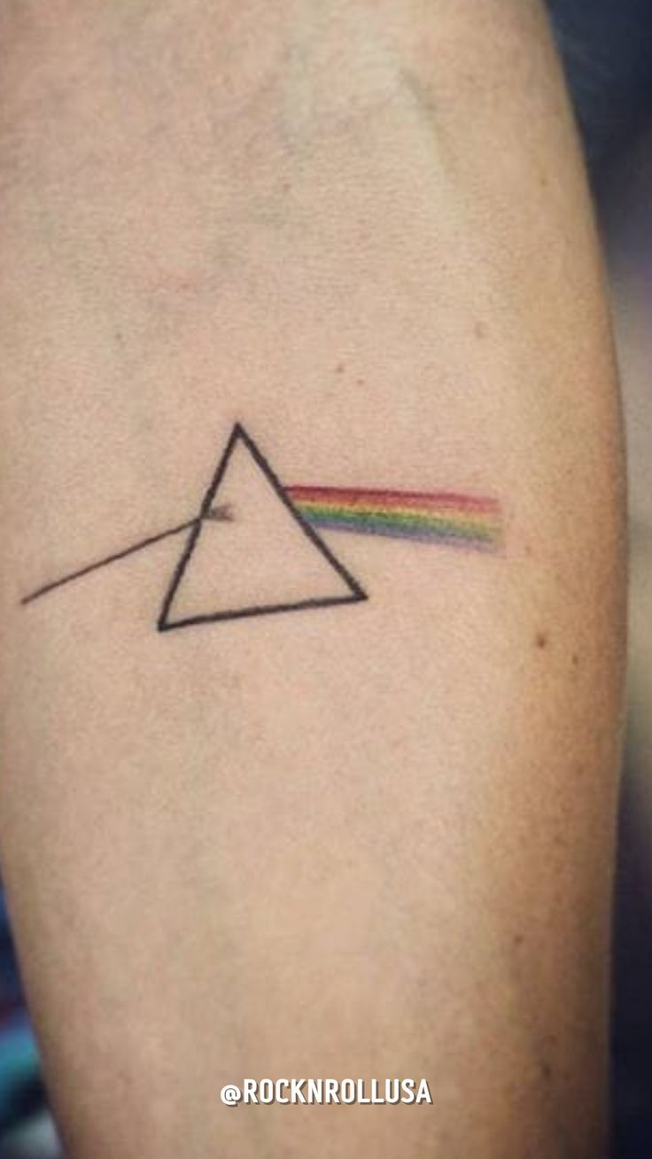 a pink floyd triangle tattoo on the left arm with a rainbow coming out of it