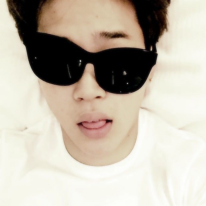 a young man wearing black sunglasses on top of a bed