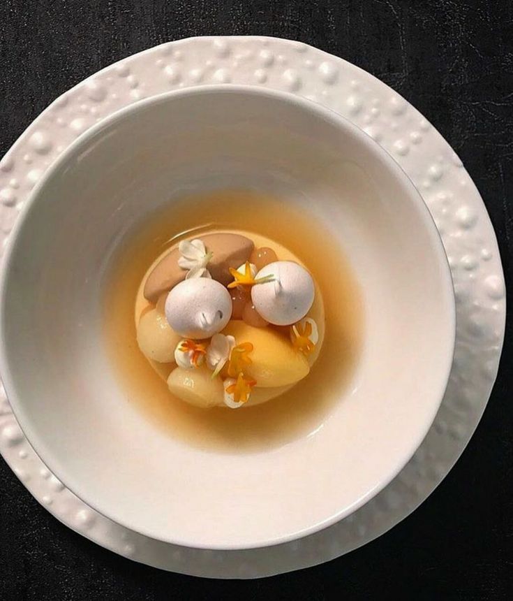 a white bowl filled with food on top of a black table next to a spoon