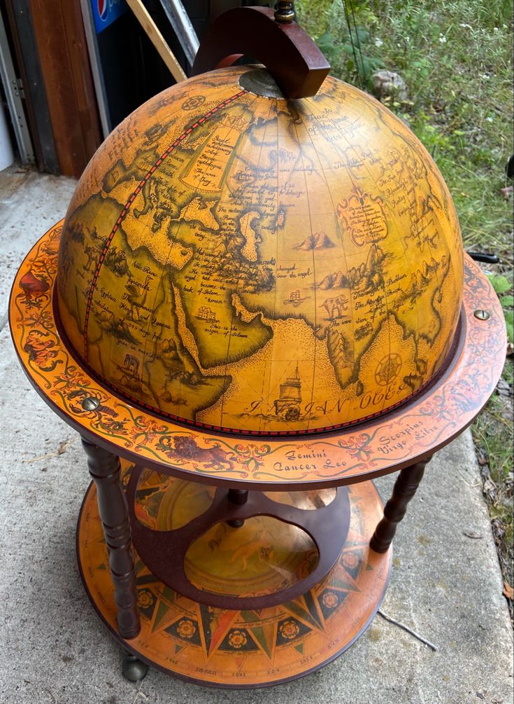 an old globe sitting on top of a wooden stand