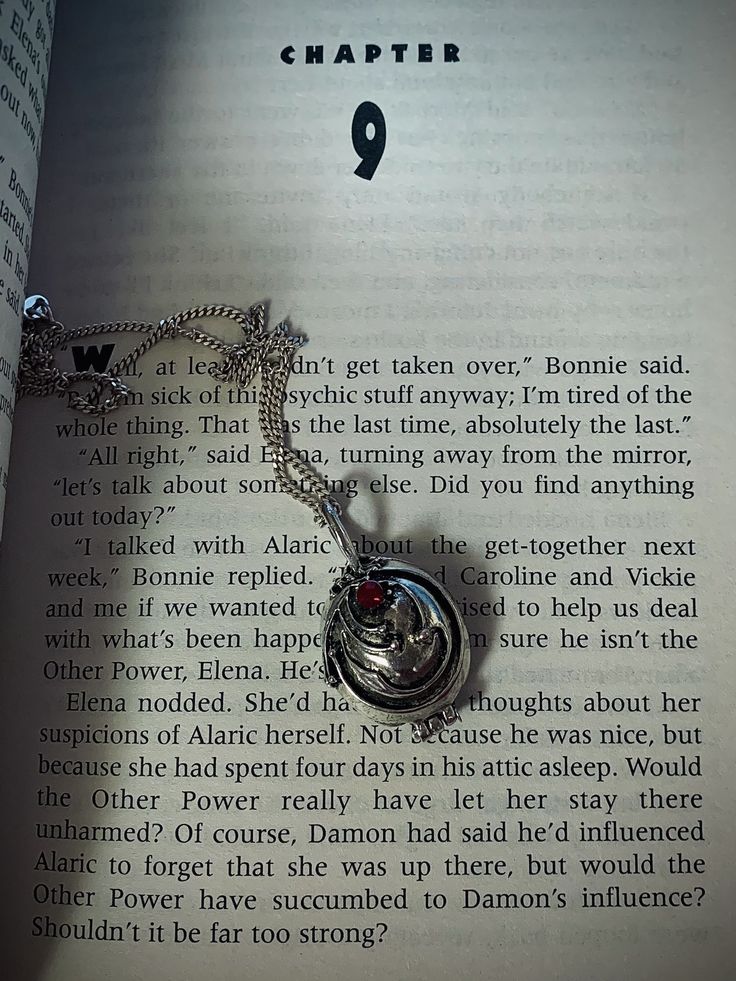 an open book with a silver necklace on it's page and the words harry potter written in english