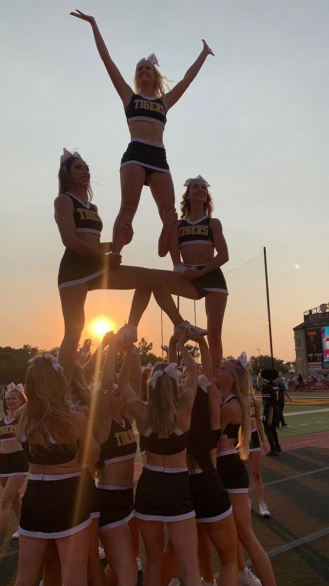 the cheerleaders are doing tricks for the crowd at the football game as the sun sets