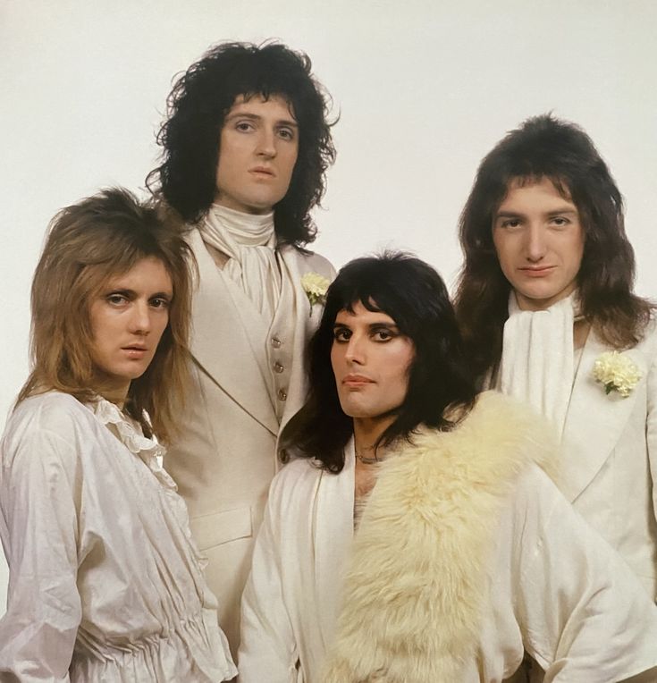 four people in white outfits standing next to each other with long hair and fur collars