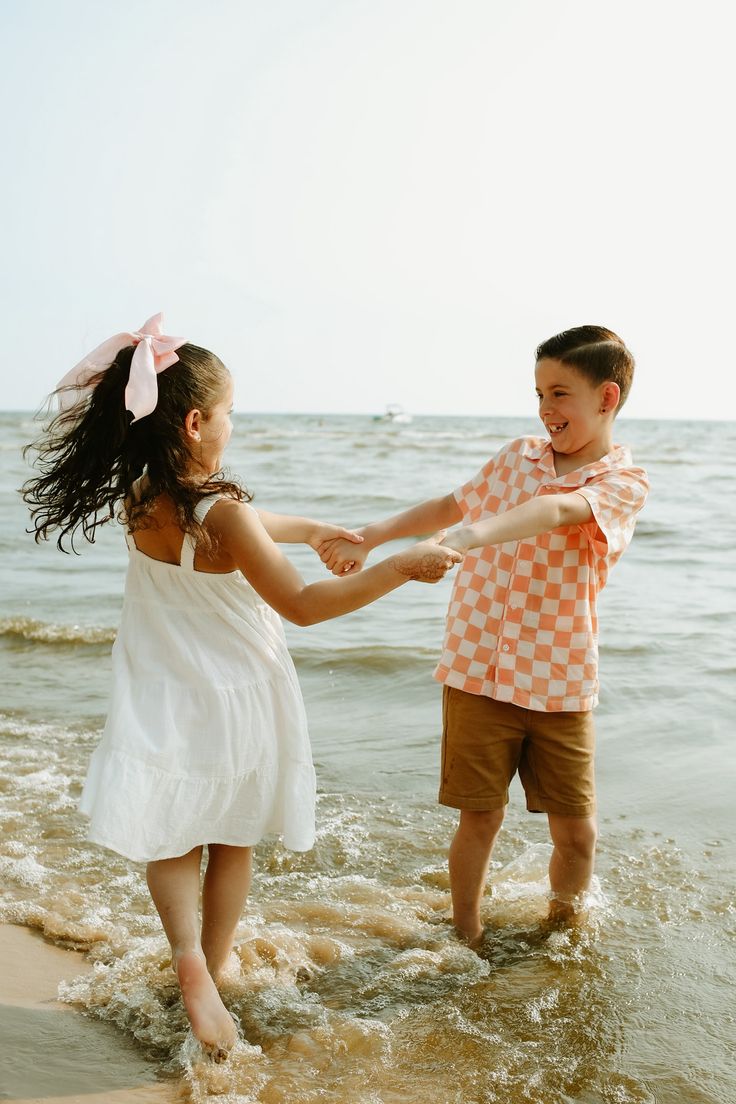 two children are playing in the water at the beach with their arms around each other